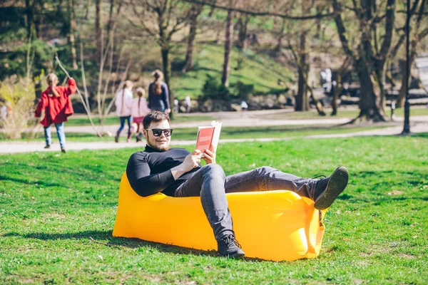 책 읽기 개념. 팽창식 매트리스에 도시 공원에서 남자 — 스톡 사진