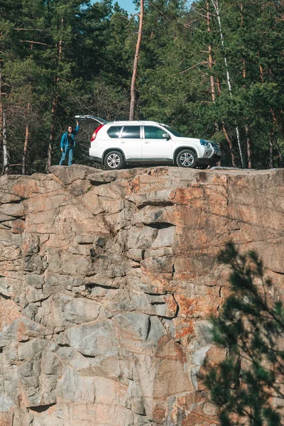 Woman looking in suv car trunk at rocky cliff — Stock Photo, Image