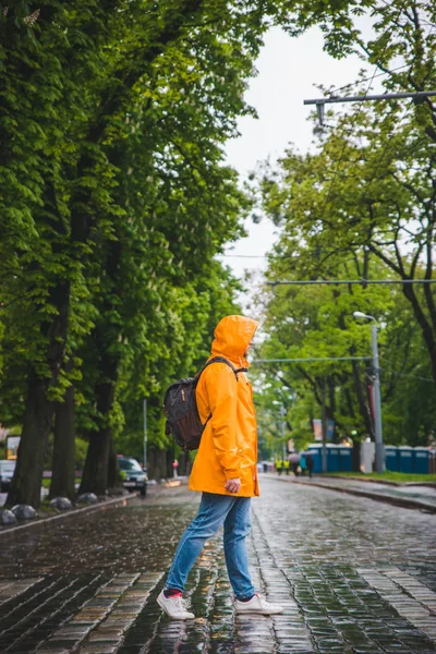 Uomo che attraversa la strada in impermeabile giallo. tempo nuvoloso — Foto Stock