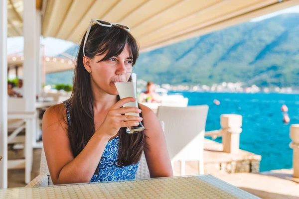 Kvinna dricka saft när man sitter i café till sjöss beach — Stockfoto