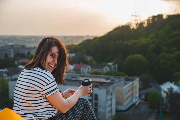 Woman drinking coffee with beautiful view of sunset over lviv city in ukraine — Stock Photo, Image