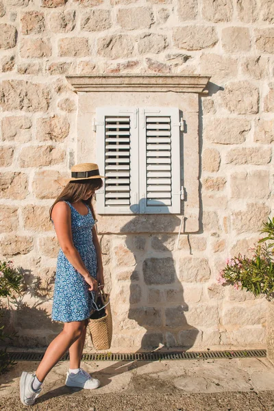 Kvinna poserar framför stenmuren med trä fönster med slutare — Stockfoto