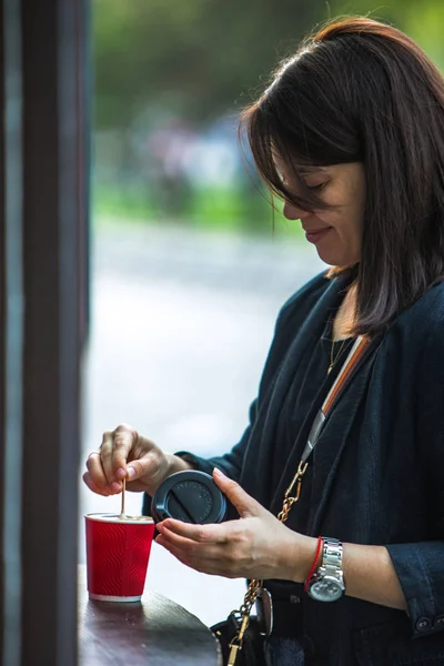 Woman put sugar in red paper coffee cup — Stock Photo, Image