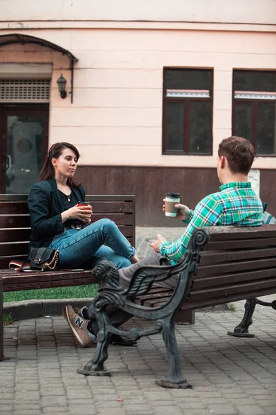 Sorrindo casal sentado no banco conversando uns com os outros beber café — Fotografia de Stock