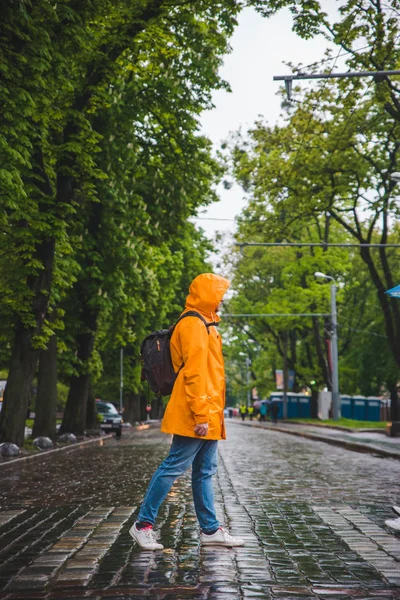 Homme traversant la rue en imperméable jaune. temps couvert — Photo