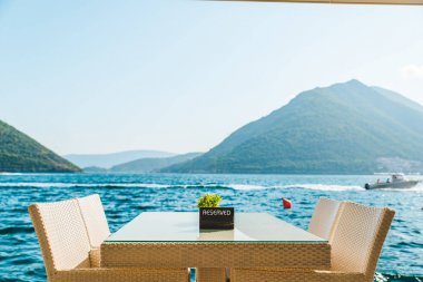 güzel bir deniz ve dağ manzarası ile sahilde Cafe tablo. üzerinde ayrılmış plaka