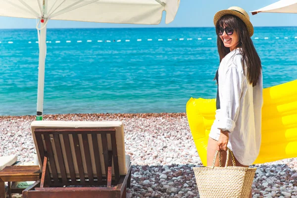 Frau mit gelber aufblasbarer Matratze am Strand. Liegestühle. — Stockfoto