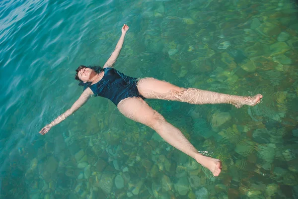 Jeune femme nageant dans l'eau bleue azur — Photo