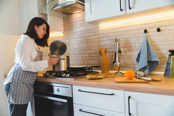 Mujer comprobando olla con agua hirviendo en la cocina — Foto de Stock