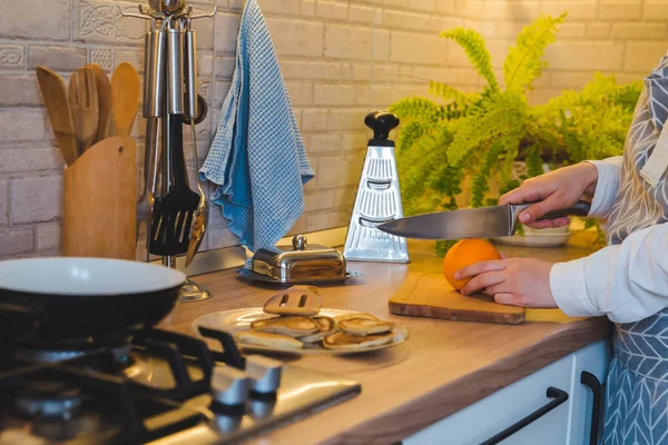 Mujer cortando naranja en la cocina doméstica — Foto de Stock