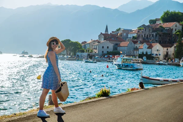 Junge hübsche Frau, die am Stadtkai spaziert. Meer und Berge im Hintergrund — Stockfoto