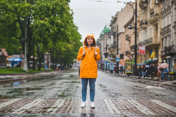 Nő az utca közepén átkelés út sárga esőkabátban — Stock Fotó