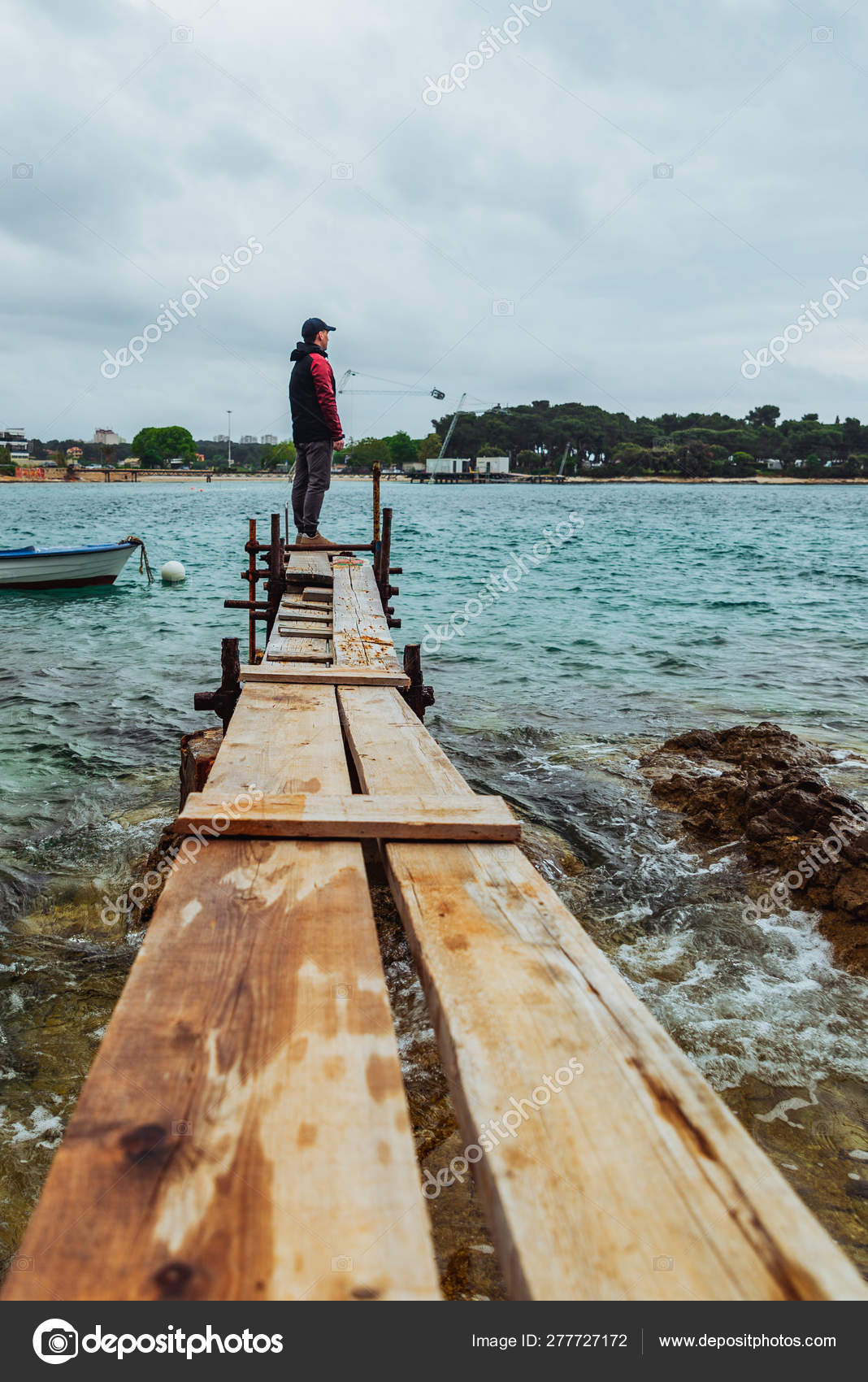 Man standing at edge of the small fishing pier looking at stormy