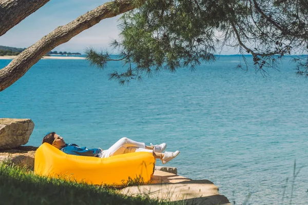 Deniz kıyısındaki sarı kanepede dinlenen kadın. — Stok fotoğraf