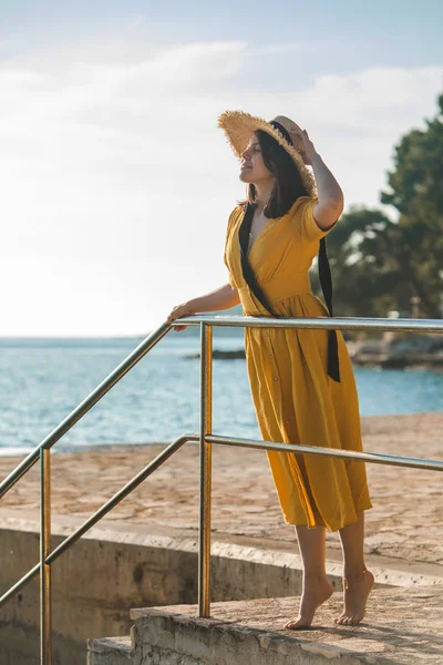 Kvinna i gult ljus sommarklänning på Stone Beach nära havet — Stockfoto