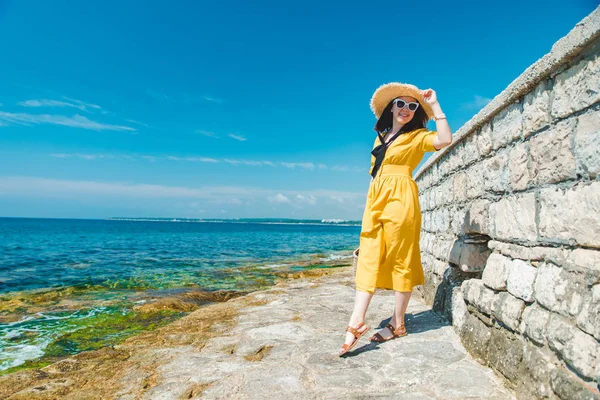 Frau in gelbem Kleid am Meeresstrand mit Strohhut — Stockfoto