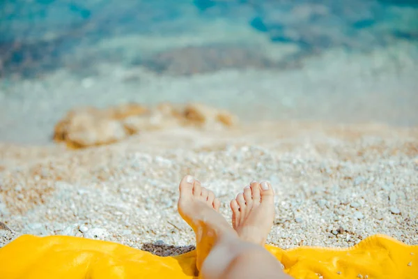Nő lábak sárga takaró a napfényes strandon közelről — Stock Fotó