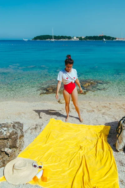 Giovane bella donna in costume da bagno rosso e t-shirt bianca sulla spiaggia del mare — Foto Stock