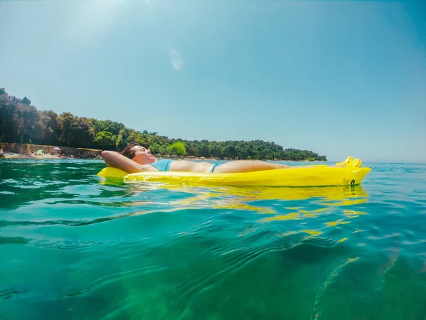 Mujer joven que pone en colchón inflable en agua de mar — Foto de Stock