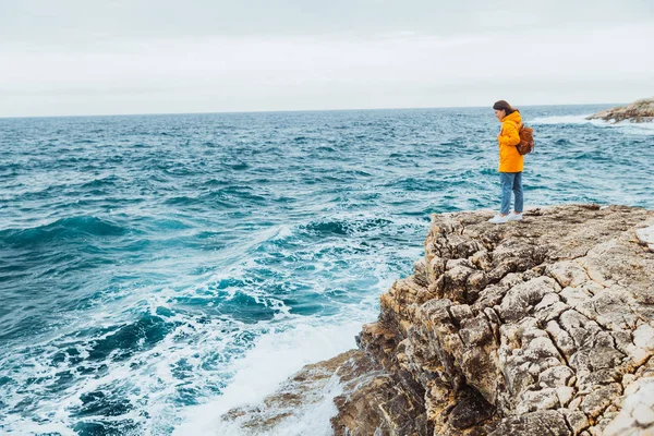 Mulher de pé no penhasco olhando para o mar — Fotografia de Stock