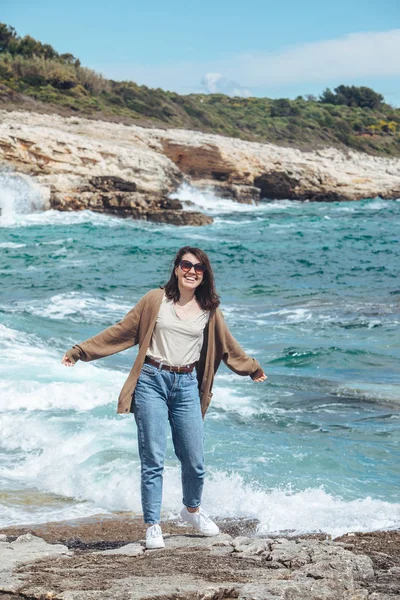 Kvinna promenader vid steniga havet stranden på solig blåsig dag. sommarsemester — Stockfoto