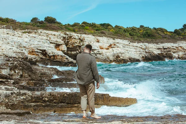 Homem andando pela praia rochosa em férias de verão dia ventoso. desfrutar de vista mar — Fotografia de Stock