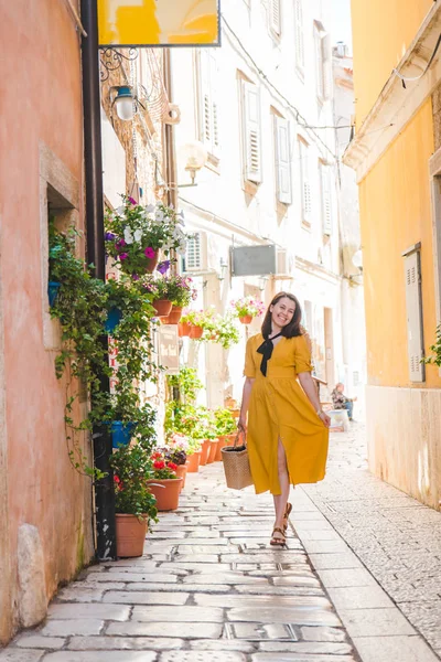 Turistická žena ve žlutém slunci chůze po malé chorvatské městské ulici — Stock fotografie