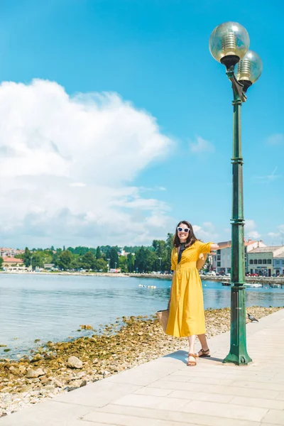 Žena, která za letního dne kráčí po mořském molu ve žlutých šatech — Stock fotografie
