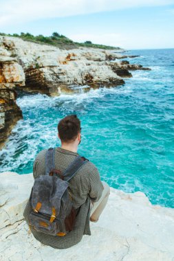 şehir manzarası zevk uçurumun üzerinde oturan sırt çantası ile adam