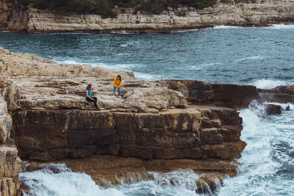 Due giovani donne adulte a scogliera guardando mare tempesta — Foto Stock