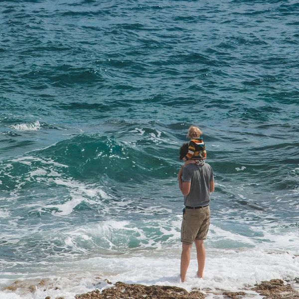 Jeune père tenant enfant sur les épaules marchant sur la plage de la mer — Photo