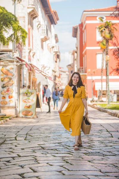 Mulher em vestido amarelo com pouco chapéu de palha andando pela cidade turística velha na croácia — Fotografia de Stock