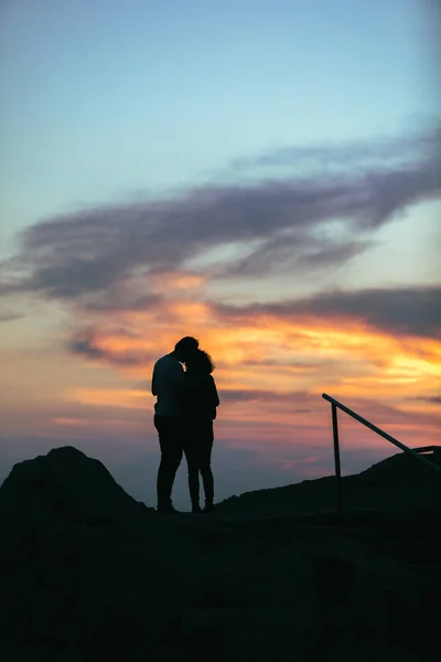 一对夫妇在日落时拥抱在悬崖上。恋人剪影 — 图库照片