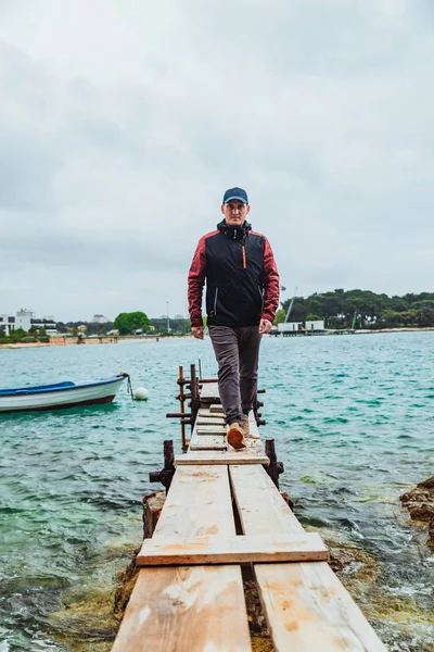 Mann zu Fuß durch kleine hölzerne Seebrücke bewölkt Wetter stürmte Meer auf Hintergrund — Stockfoto