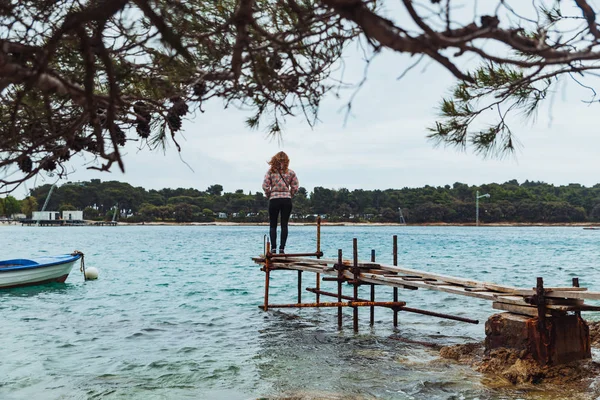 Sakin denize bakan balıkçı iskelesi üzerinde duran kadın — Stok fotoğraf
