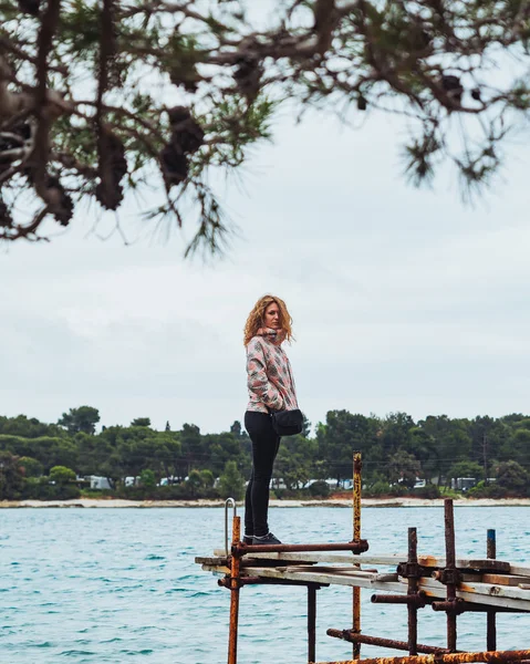 Kvinna som står vid gamla Fiskebryggan tittar på havet — Stockfoto