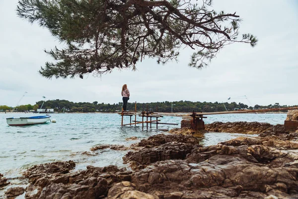 Γυναίκα στέκεται στο αλιευτικό προβλήτα κοιτάζοντας δεν ήρεμη θάλασσα — Φωτογραφία Αρχείου