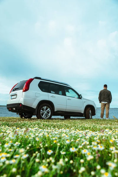 Un hombre parado cerca de un auto en la playa. concepto de viaje por carretera — Foto de Stock