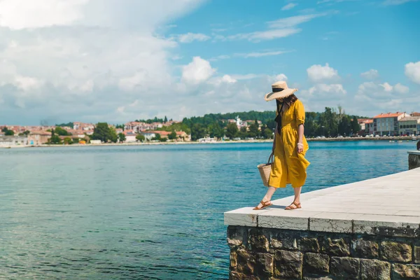 Donna in piedi sul molo di pietra bordo guardando il mare. prendisole giallo — Foto Stock