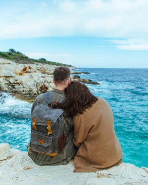 uçurumun kenarında oturan çift denize bakıyor