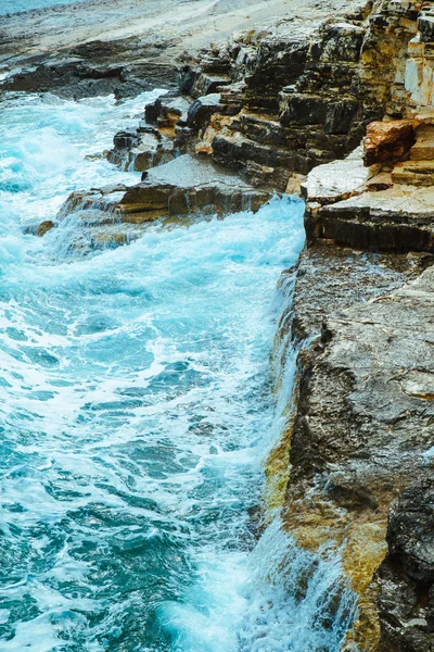 Вид на воду з хвилями зі скелястою скелею — стокове фото