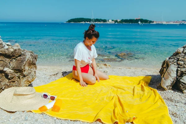 Mulher sentada no cobertor amarelo na praia olhando para o mar — Fotografia de Stock