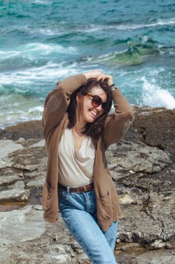 Deniz kıyısında doğanın gücünün tadını çıkaran bir kadın. Rüzgarlı hava