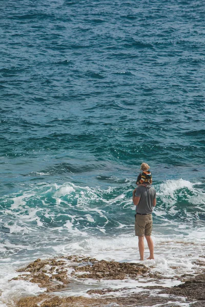 Joven padre sosteniendo niño sobre hombros caminando por mar playa — Foto de Stock