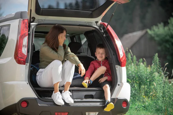 Young mother with kid boy sitting in car trunk resting in summer sunny day — Stock Photo, Image