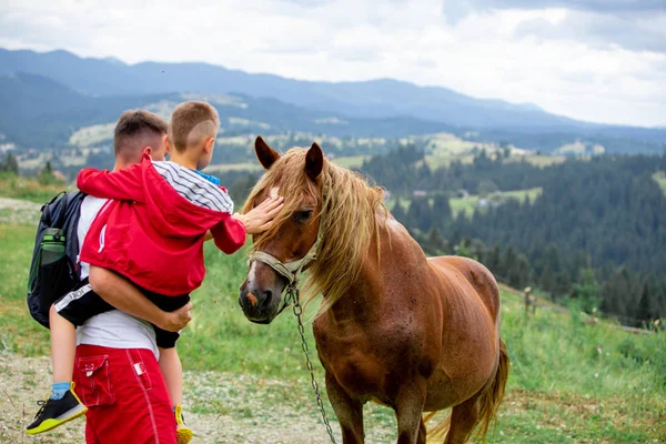 Hombre con niño mascota las montañas de caballo en el fondo — Foto de Stock