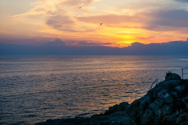 kayalık uçurum üzerinde bulutlar ile denizde gün batımı