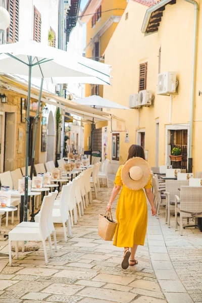 Nő sárga ruhában Walking By Resort City Street között kávézó étterem asztalok — Stock Fotó