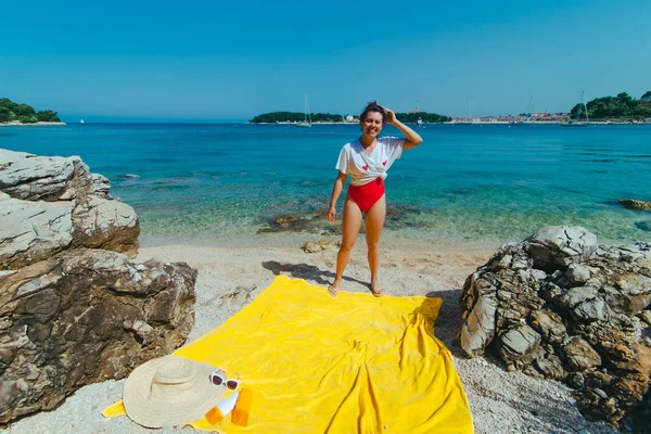 Giovane bella donna in costume da bagno rosso e t-shirt bianca sulla spiaggia del mare — Foto Stock