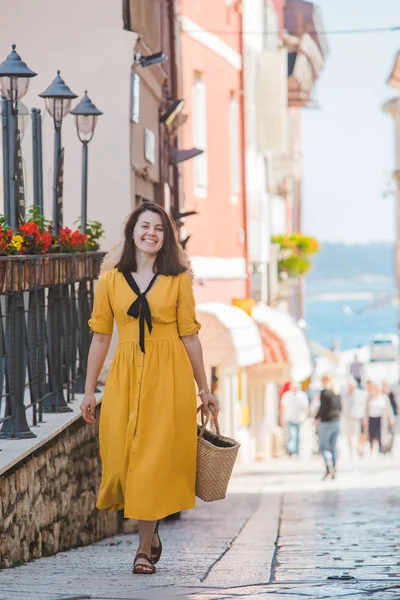 Giovane bella donna in abito giallo a piedi da piccole strade della città parenzo mare sullo sfondo — Foto Stock